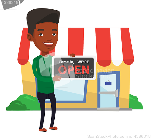 Image of African shop owner holding open signboard.