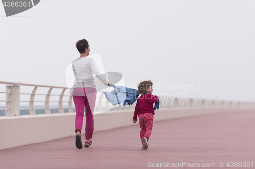 Image of mother and cute little girl on the promenade by the sea