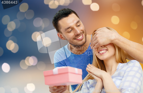 Image of happy couple with present over lights background