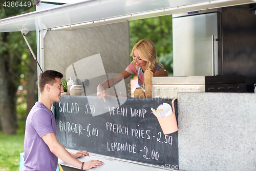 Image of saleswoman at food truck serving male customer