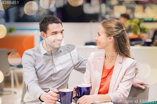 Image of happy couple with shopping bags drinking coffee