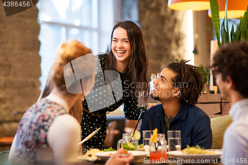 Image of happy friends eating at restaurant