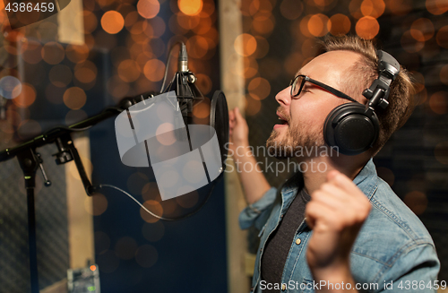 Image of man with headphones singing at recording studio