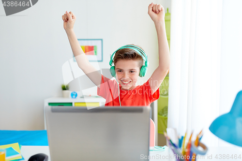 Image of boy with headphones playing video game on laptop