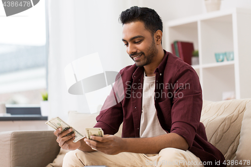 Image of smiling man counting money at home