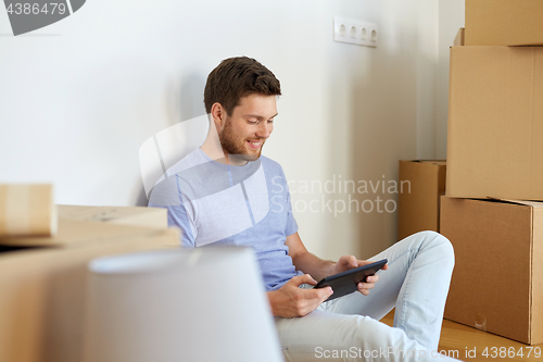 Image of man with tablet pc and boxes moving to new home