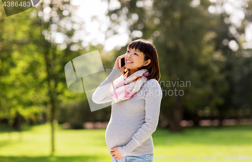 Image of pregnant asian woman calling on smartphone at park