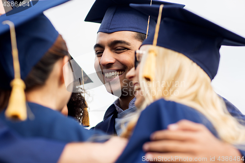 Image of happy students or bachelors in mortar boards