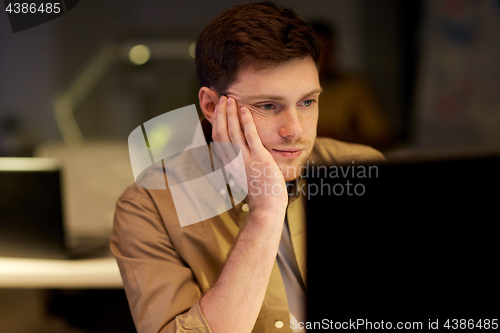 Image of tired or bored man on table at night office