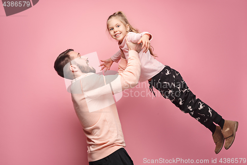 Image of cheerful father playing with daughter on pink