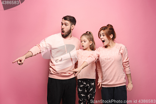 Image of Surprised young family on pink
