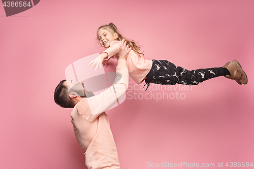 Image of cheerful father playing with daughter on pink
