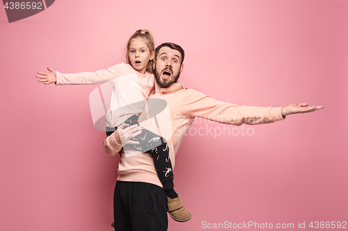 Image of cheerful father playing with daughter on pink