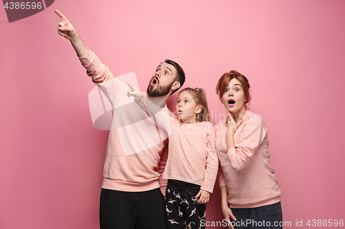 Image of Surprised young family on pink