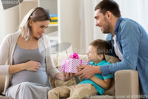 Image of family giving present to pregnant mother at home