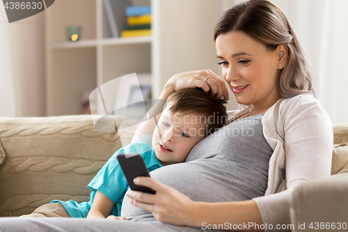 Image of pregnant mother and son with smartphone at home