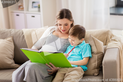 Image of pregnant mother and little son with book at home