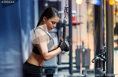 Image of woman flexing arm muscles on cable machine in gym