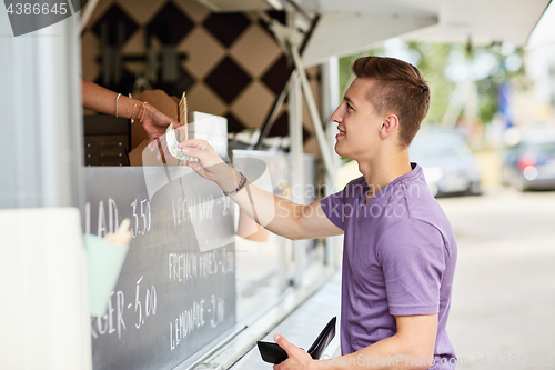 Image of happy young man paying money at food truck