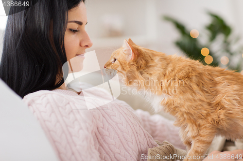 Image of close up of owner with red cat in bed at home