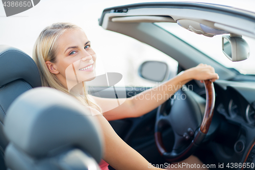 Image of happy young woman driving convertible car