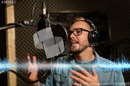 Image of man with headphones singing at recording studio