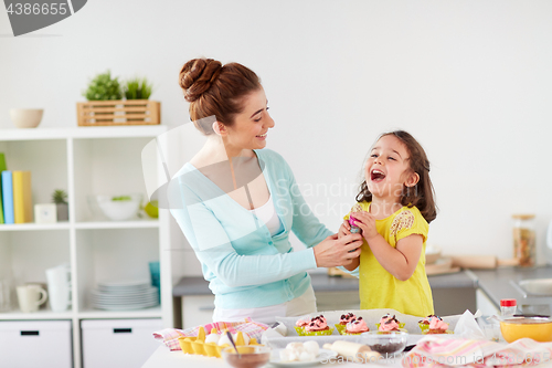 Image of mother and daughter cooking cupcakes at home