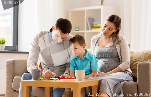 Image of father, pregnant mother and son drawing at home