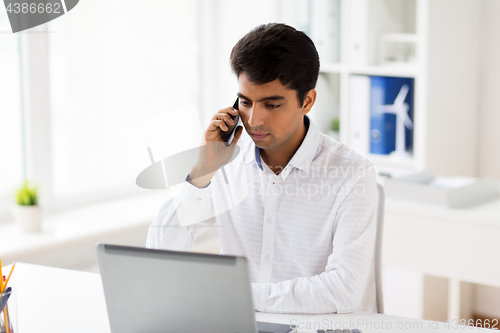 Image of businessman calling on smartphone at office