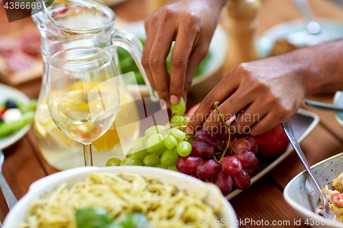 Image of hands taking grape from plate with fruits