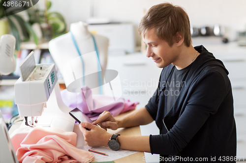 Image of fashion designer with tablet pc working at studio