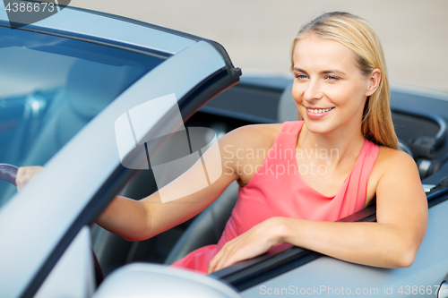 Image of happy young woman driving convertible car