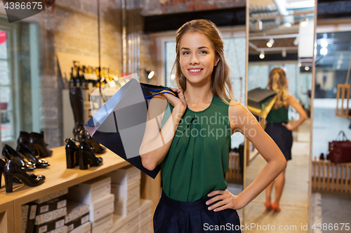 Image of happy young woman with shopping bags at shoestore