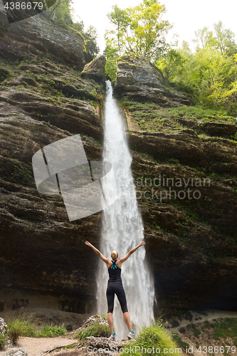 Image of Active woman raising arms inhaling fresh air, feeling relaxed in nature.