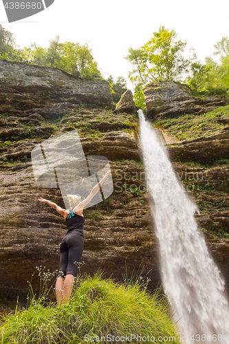 Image of Active woman raising arms inhaling fresh air, feeling relaxed in nature.