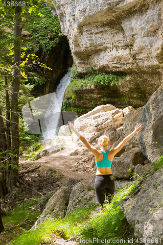 Image of Active woman raising arms inhaling fresh air, feeling relaxed in nature.