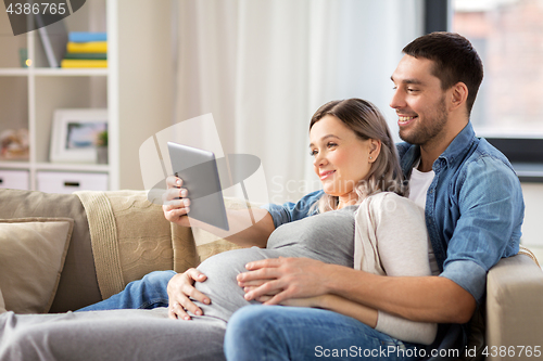 Image of man and pregnant woman with tablet pc at home
