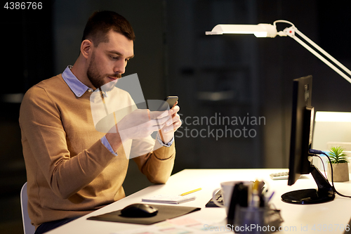 Image of man with smartphone working late at night office