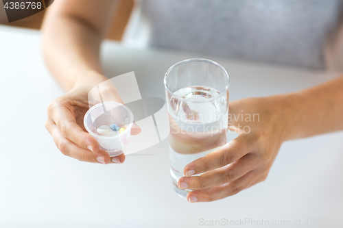 Image of close up of hands with pills and glass of water