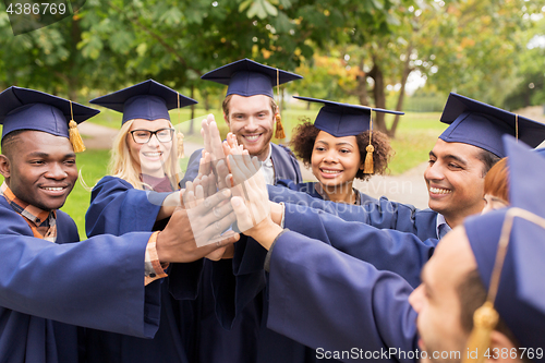 Image of happy students in mortar boards making high five