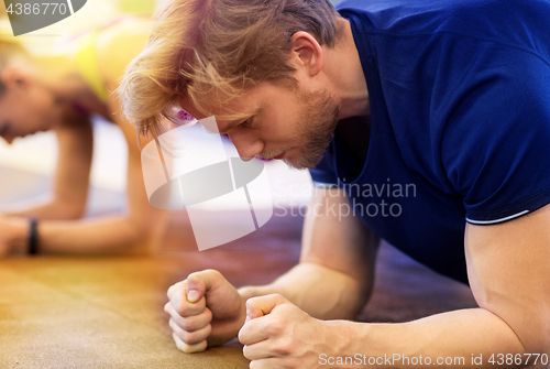 Image of close up of man at training doing plank in gym