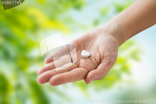 Image of close up of hand holding medicine heart pill