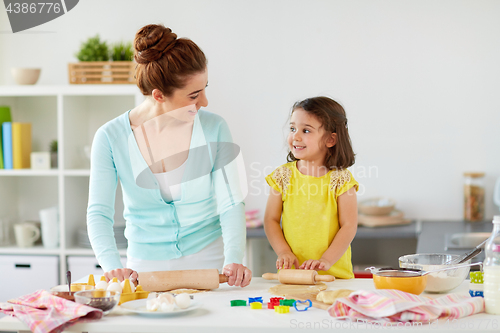 Image of happy mother and daughter making cookies at home