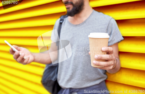 Image of man with coffee cup and smartphone over wall