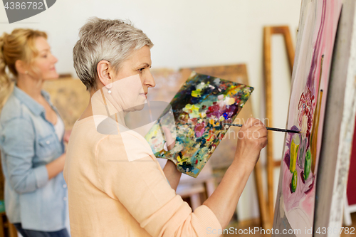 Image of senior woman painting at art school studio