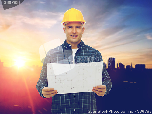 Image of male builder in yellow hard hat with blueprint