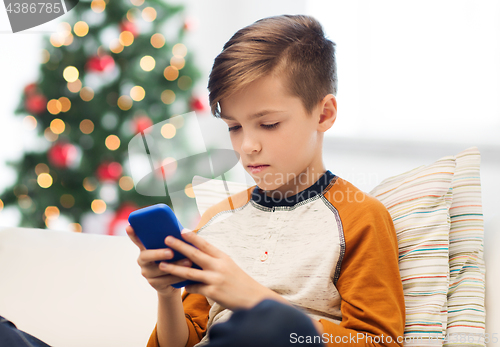 Image of boy with smartphone at home at christmas