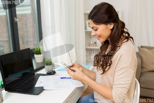 Image of woman with papers and smartphone working at home
