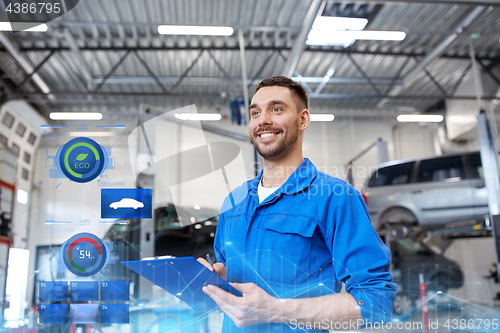 Image of happy mechanic man with clipboard at car workshop