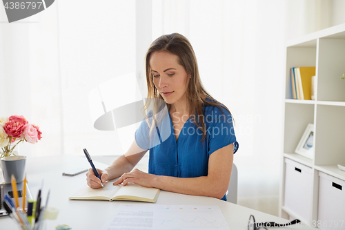 Image of woman writing to notebook at office